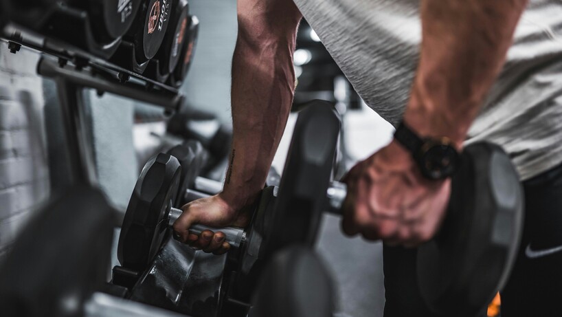 Man taking Dumbbells off of a rack