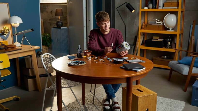 Wide shot of a man building the Lego Hubble telescope