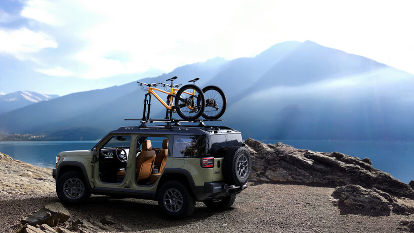 Green Jeep Recon by a lake with two bikes