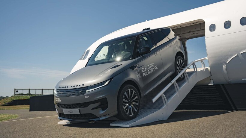 Prototype electric range rover emerging from the front of a plane