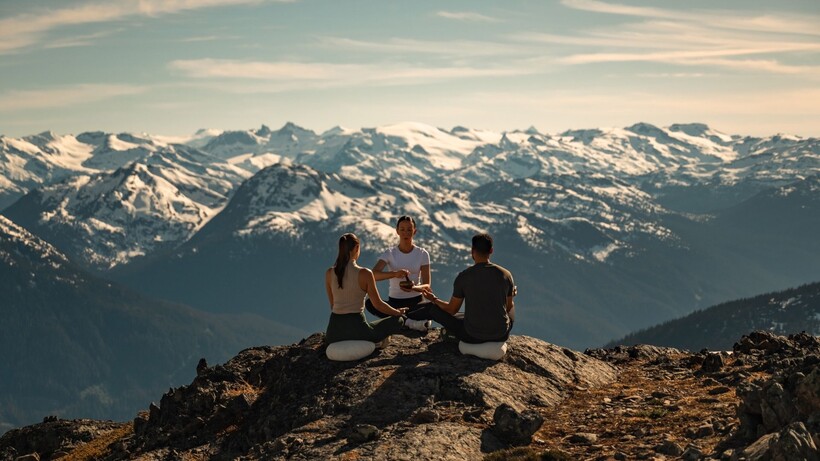 Guests practising guided wellness on a secluded mountaintop overlooking the Coast Mountains near Whistler