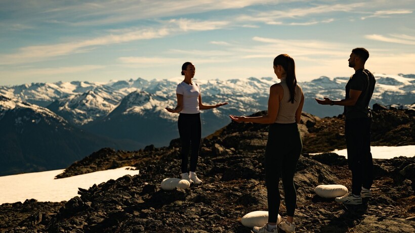 Guests practising guided wellness on a secluded mountaintop overlooking the Coast Mountains near Whistler