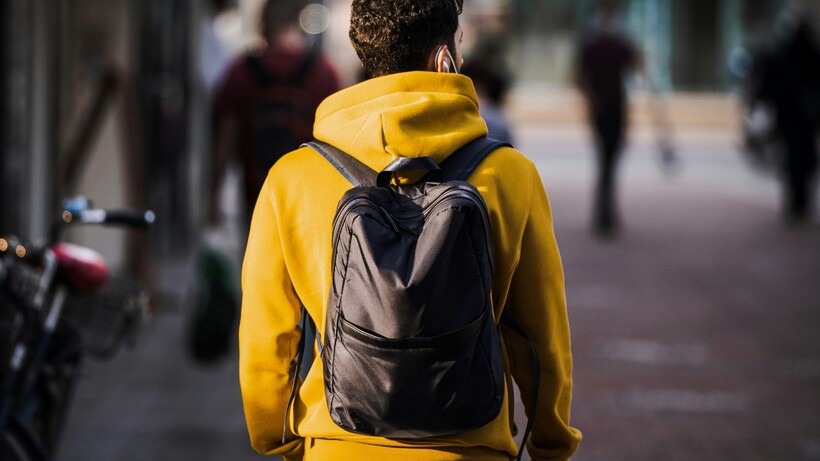 Man in yellow hoodie wearing a backpack