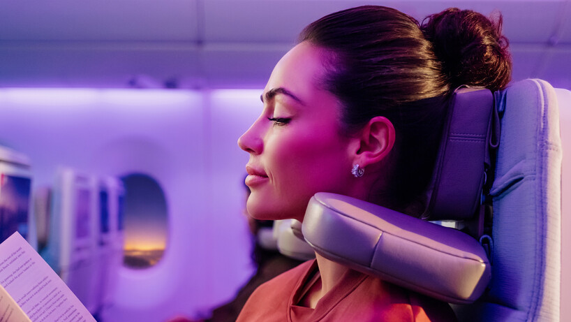 Emirates image showing a woman relaxing with the new economy seat headrest