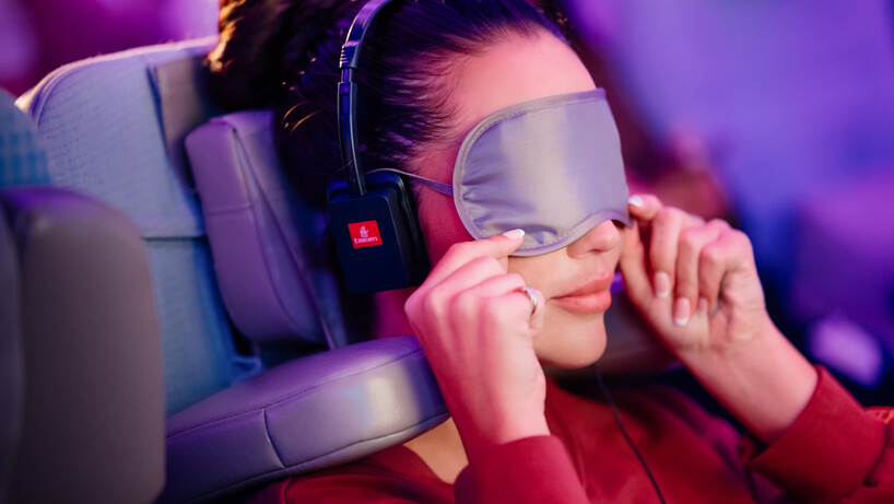Woman wearing a sleep mask while sitting in one of the seats with Emirate's new head pillow
